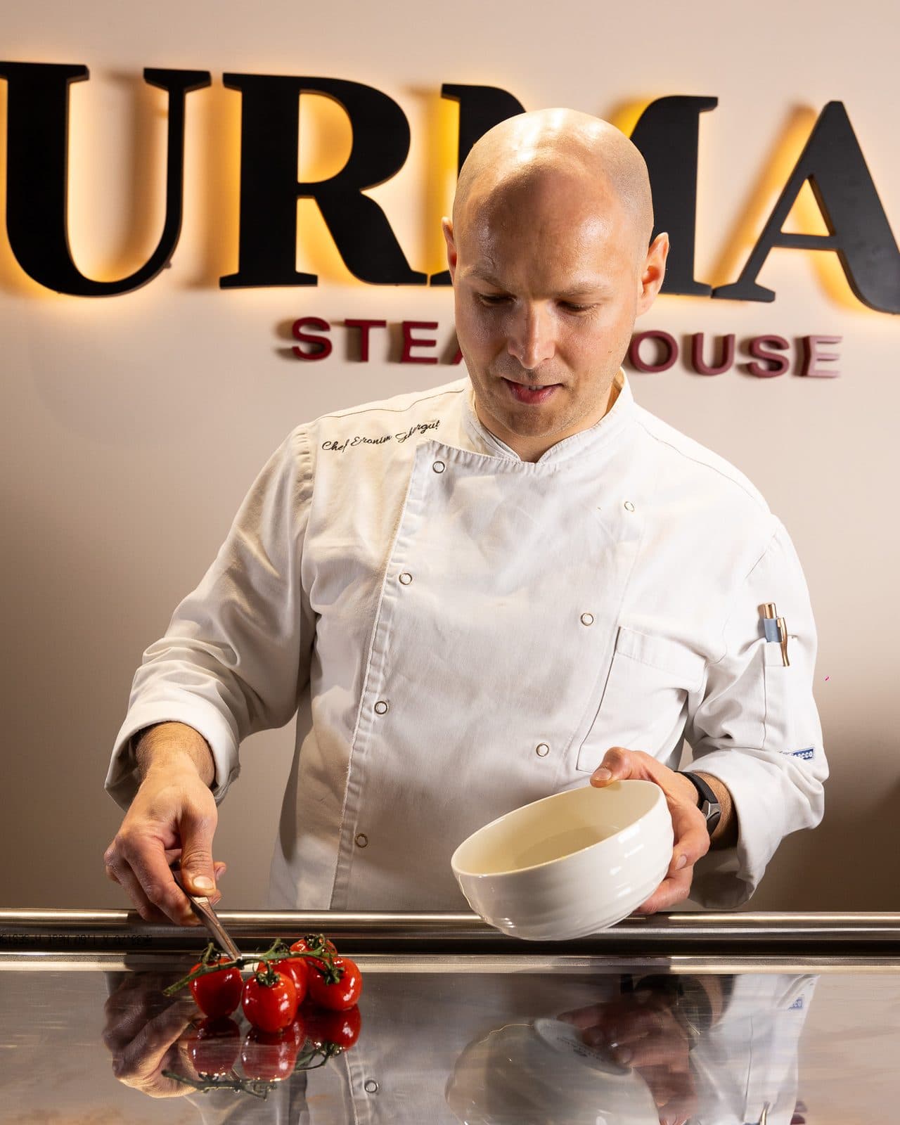 Chef finalizând un platou în fața emblemei